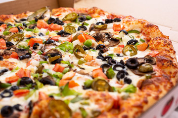 A view of a meat and veggie pizza pie, in a restaurant or kitchen setting.