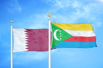 Qatar and Comoros two flags on flagpoles and blue cloudy sky