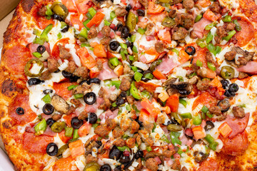 A background image of a meat and veggie pizza pie, seen inside a cardboard box.