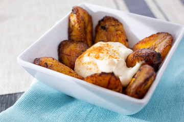 A closeup view of a bowl of fried plantains in a restaurant or kitchen setting. © DAVID
