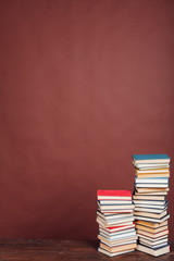 many stacks of educational books for learning the preparation for exams on a brown background