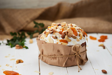 Easter cake decorated by nuts and dried fruits on white wooden background, Traditional Kulich, Paska  ready for celebration
