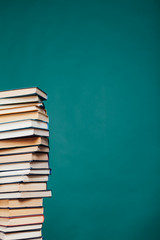 many stacks of educational books for learning preparation for college exams on a green background