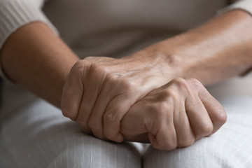 Middle aged senior woman holding wrinkled hands on lap close up. Confused mature elderly grandmother suffering from solitude loneliness, worrying about hard decision, nursing home retirement life.
