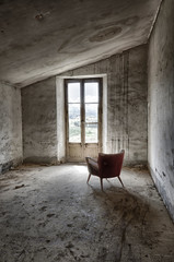 Butaca a contraluz en habitación sucia y abandonada iluminada por una ventana.