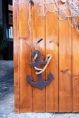 Anchor and fishing net on a wooden door. Nautical style exterior decoration in Nessebar, Bulgaria. Maritime background texture.