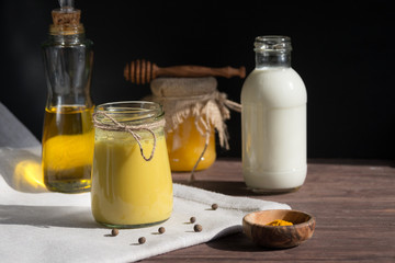 Turmeric-based golden milk healing drink and ingredients on black background. Prevention of diseases and strengthening immunity.