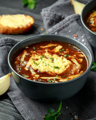 French onion soup with cheese toast on rustic background