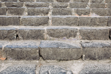 Stone stairs made of gray rough old stone on the street of a European town. Granite staircase background close up, urban details