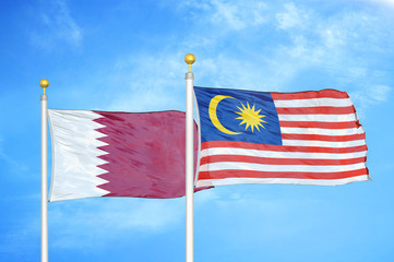 Qatar and Malaysia two flags on flagpoles and blue cloudy sky
