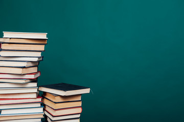 many stacks of educational books for learning preparation for college exams on a green background