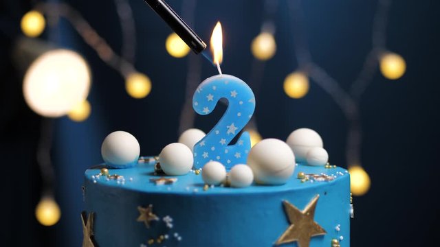 Birthday cake number 2 stars sky and moon concept, blue candle is fire by lighter and then blows out. Copy space on right side of screen if required. Close-up and slow motion