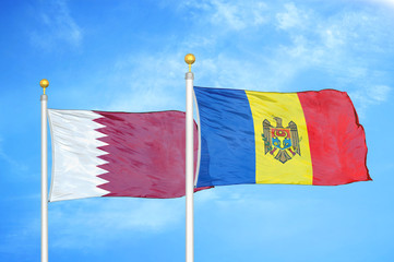 Qatar and Moldova two flags on flagpoles and blue cloudy sky