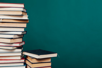 many stacks of educational books for learning preparation for college exams on a green background