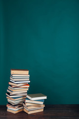 many stacks of educational books for learning preparation for college exams on a green background