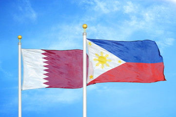 Qatar and Philippines two flags on flagpoles and blue cloudy sky