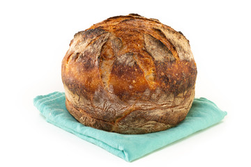 A homemade baked loaf of round artisan white sourdough bread isolated on white.