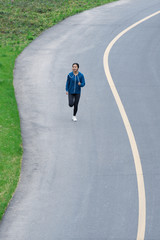 A young Asian woman is running on the road