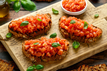 Tomato bruschetta seasoned with basil on a rustic wooden board