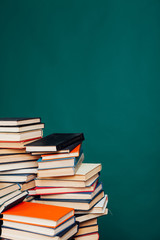 many stacks of educational books for learning preparation for college exams on a green background