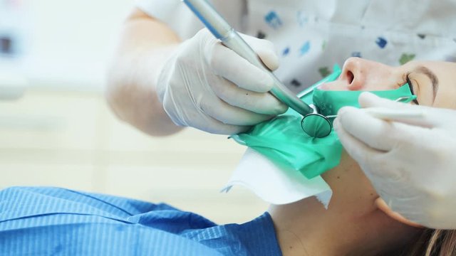A doctor in rubber gloves with a dental drill is treating teeth. Visit to the dental clinic.