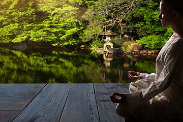 Beautiful young woman in white robe sits in meditation on the background of the zen garden..Meditation is the best way to solve the most complex problems.
