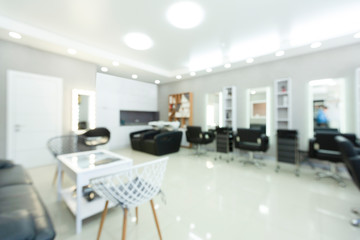 Blurry barbershop interior with black armchairs and mirrors