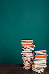 many stacks of educational books for learning preparation for college exams on a green background