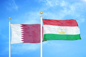 Qatar and Tajikistan two flags on flagpoles and blue cloudy sky