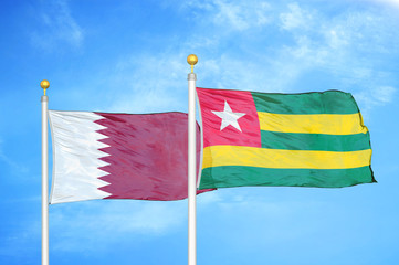 Qatar and Togo two flags on flagpoles and blue cloudy sky