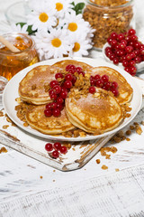 tasty pancakes with berries and honey on a white wooden background, vertical