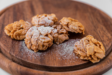 Almond cookies sprinkled with icing sugar on top on a dark brown wooden board on a white background. Great background for a cafe or restaurant menu, signboard