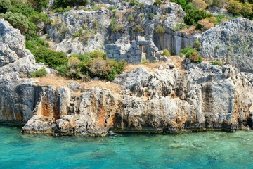 Fototapeta na wymiar Weathered ruins of famous ancient underwater town Sunken City on Kekova island, in mediterranean coastline of Antalya province,Turkey.