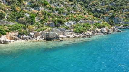 Panoramic view from tourist yacht to weathered ruins of famous ancient underwater town Sunken City on Kekova island, in mediterranean coastline of Antalya province. Popular tourist places in Turkey.