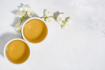 Fototapeta na wymiar two bowls with green tea and white background and jasmine, top view, closeup