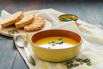 Vegetarian homemade pumpkin cream soup with seeds and bread.