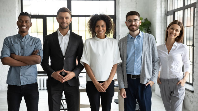 Portrait of standing in row smiling diverse team posing differently looking at camera. Happy young multiethnic corporate staff, bank workers photo shoot, HR agency recruitments.