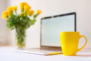 Laptop mockup on work desk in sunset. Close-up laptop with flowers, coffee, with morning light. Modern, thin laptop design.White. Isolated screen for mockup. Laptop profile. Home office