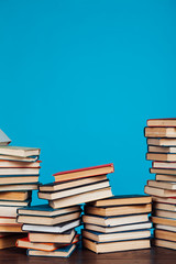 many stacks of educational books for learning preparation for college exams on a blue background
