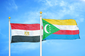 Egypt and Comoros two flags on flagpoles and blue cloudy sky