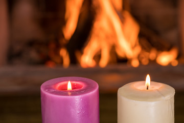 Cozy scene before fireplace with two burning candles.