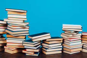 many stacks of educational books for learning preparation for college exams on a blue background