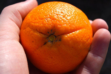 An orange in woman's hand