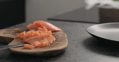 chopped salted trout with knife on olive wood board
