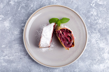dessert of cherry strudel on a plate, gray concrete background