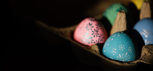 Panorama mit bunte, selbst angemalten Ostereier, in Handarbeit. Zu Hause in einem Eierkarton. Vogelperspektive mit selektiver Schärfe im Querformat und viel Platz für Text
