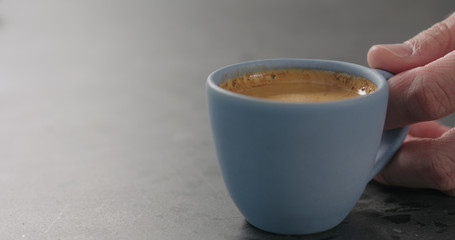 man hand put blue cup with fresh espresso on concrete surface