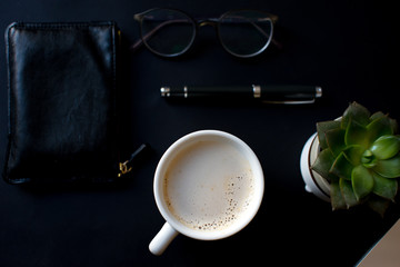 Top view office table concept with laptop coffee cup,  notebook, glasses, succulent on black table background. Mock up notes, copy space