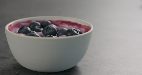 blueberries in yogurt in white bowl on concrete surface