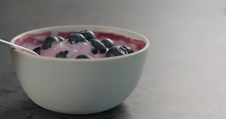 Fototapeta na wymiar eat yogurt with blueberries from white bowl on concrete surface